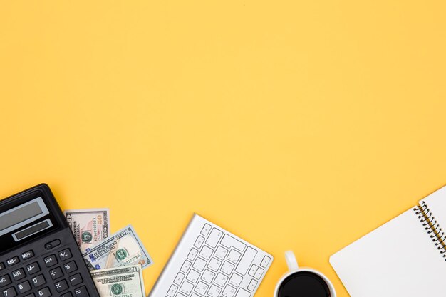 Calculator money notepad and keyboard on yellow background flat lay