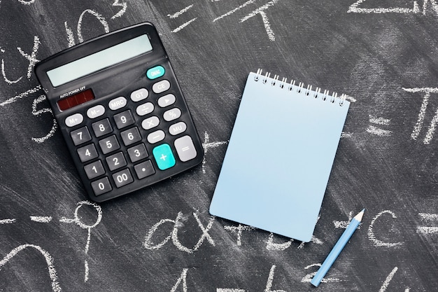 Calculator and notebook on chalkboard