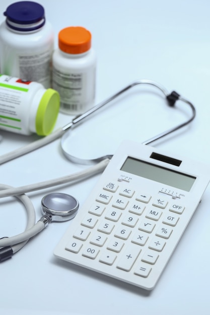 Free Photo calculator, stethoscope and medicine bottles on white background