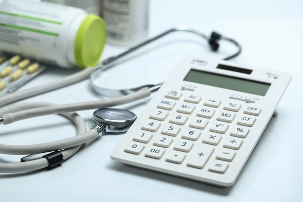 Free Photo calculator, stethoscope and medicine bottles on white background