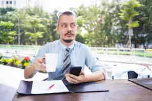 Free photo calm pensive businessman with beard drinking coffee