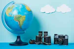 Free photo camera and binoculars near globe and clouds