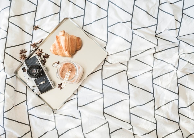 Free photo camera and breakfast food on bed