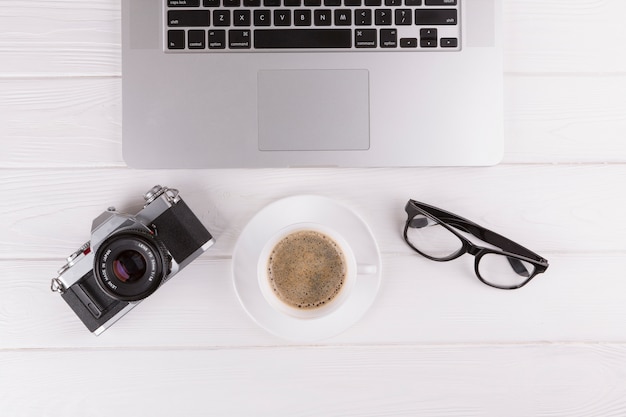 Camera, eyeglasses, cup and laptop