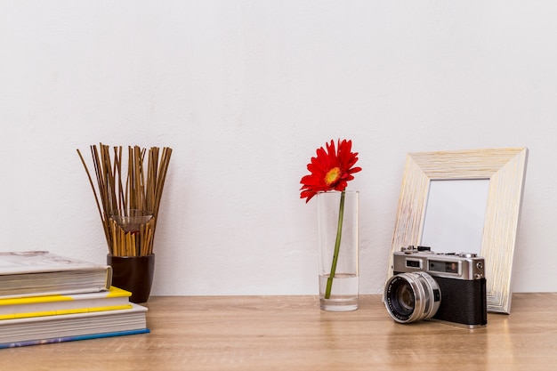 Free photo camera flower photo frame and books on table