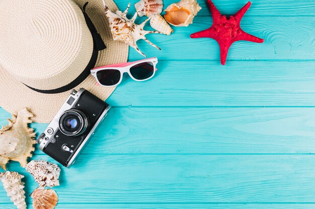 Camera and hat near sunglasses and seashells