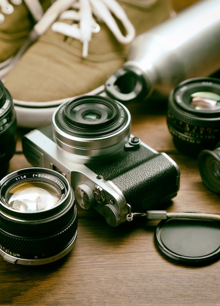 Free Photo camera, lens, binocular, canvas shoes, sports bottle on the retro wooden table