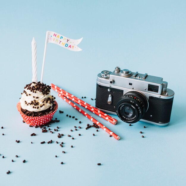 Camera and straws near birthday muffin