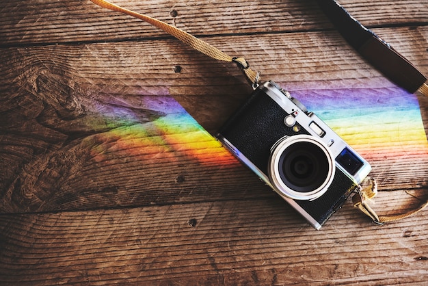 Free photo camera on wooden table with reflection of prism lights