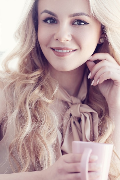 candid beautiful blonde woman portrait with tea or coffee pink cup