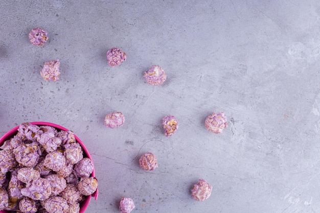 Candied popcron inside and scattered around a small bucket on marble background. High quality photo