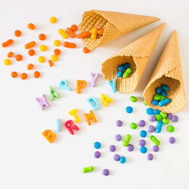 Candies spilling from waffle ice cream cone on happy birthday