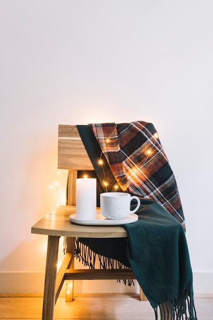 Free photo candle with cup on wooden chair