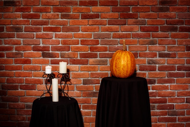 Free Photo candles and pumpkin on table over brick wall. halloween. copy space.