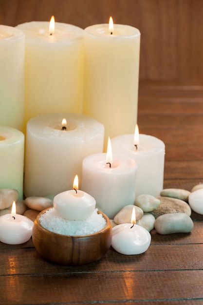 Candles with massage oil bottles and sea salt in wooden bowl