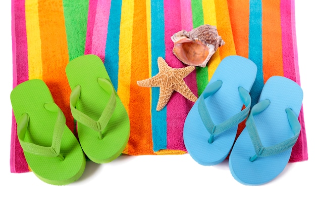 Candy stripe beach towel with flip flops, starfish and seashell isolated on white.