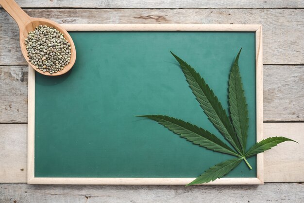 Cannabis, Cannabis seeds, Cannabis leaves, Placed on a green board on a wooden floor.