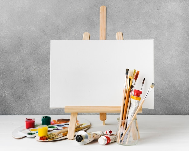 Free photo canvas on easel and watercolour paint front view