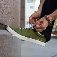 Free photo canvas sneakers green model tying shoelaces apparel ad