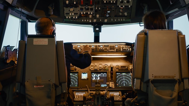 Captain and woman copilot in cockpit preparing to fly airplane, using dashboard command buttons to fix altitude and longitude control to takeoff. Aerial navigation with radar compass.