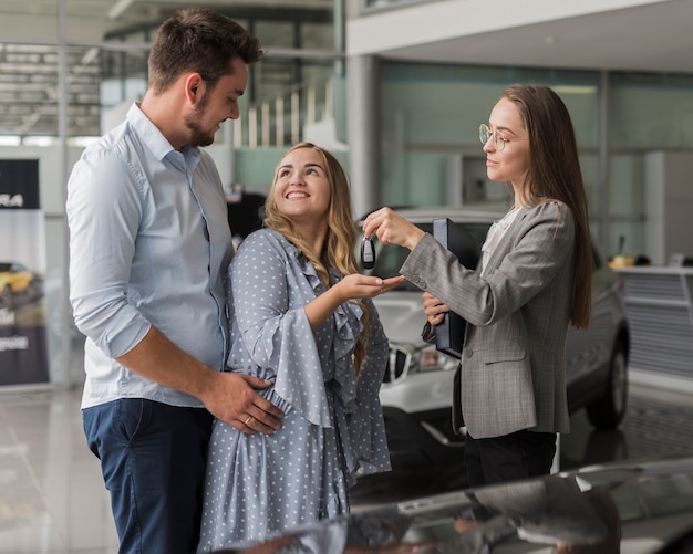 Free photo car dealer giving keys to young couple