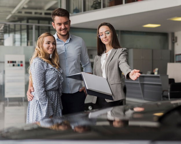 Car dealer showing a automobile to a couple