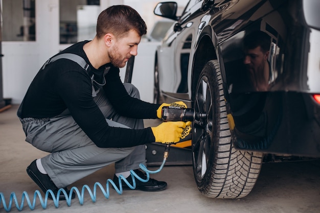 Free photo car mechanic changing wheels in car