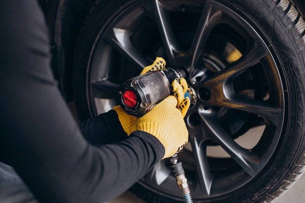 Car mechanic changing wheels in car