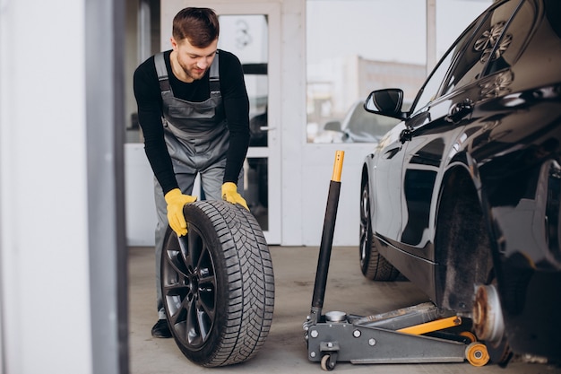 Free photo car mechanic changing wheels in car