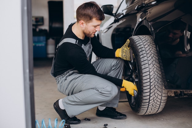 Car mechanic changing wheels in car