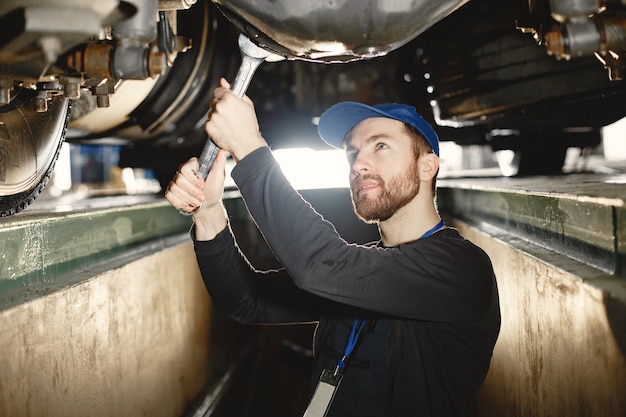 Free Photo car mechanic repairs blue car on rise in  garage