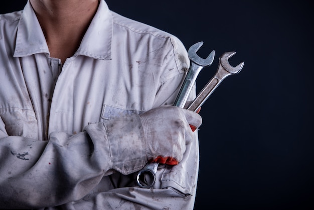 Free Photo car mechanic wearing a white uniform stand holding wrench