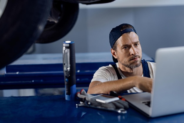 Free Photo car mechanic working on laptop at auto repair shop