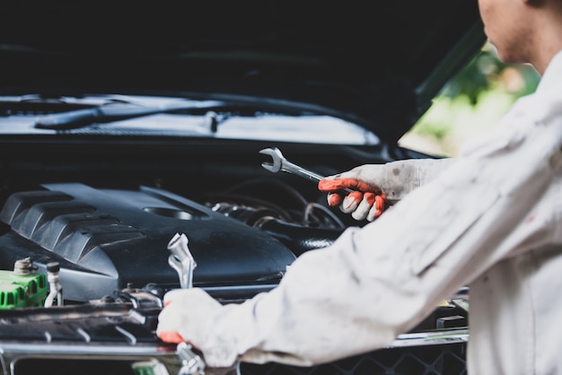 Free photo car repairman wearing a white uniform standing and holding a wrench that is an essential tool for a mechanic