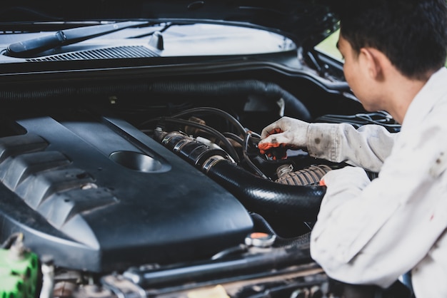 Free photo car repairman wearing a white uniform standing and holding a wrench that is an essential tool for a mechanic