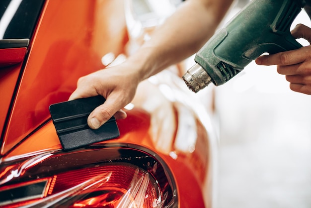 Free Photo car wrapping with foil and drying with fan at car service