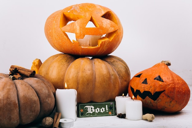 Card with lettering 'Boo' stands before scarry Halloween pumpkins