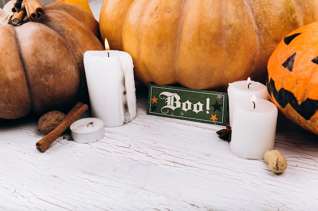 Free Photo card with lettering 'boo' stands before scarry halloween pumpkins