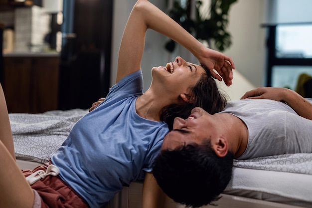 Carefree couple having fun and laughing while talking about something in the bedroom