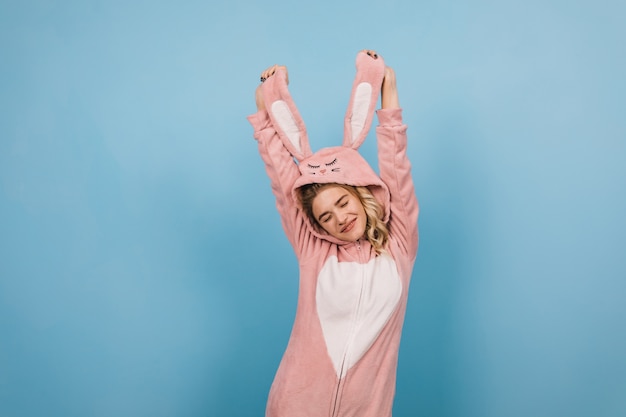 Free photo carefree female model dancing in pink kigurumi