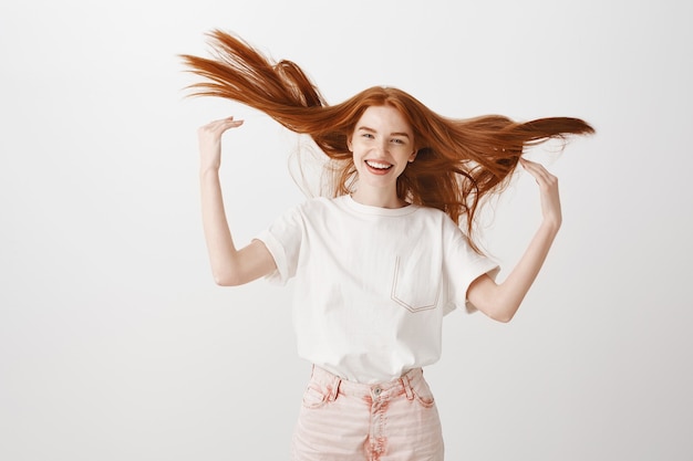 Free photo carefree happy redhead woman tossing her hair and smiling upbeat