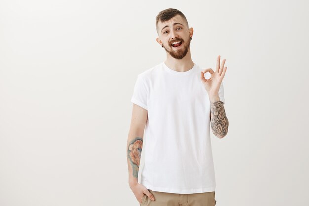 Carefree hipster guy assure all good, showing okay gesture relaxed