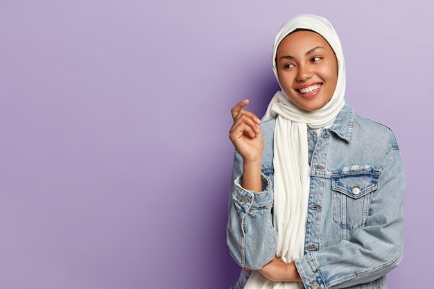 Free photo carefree optimistic female with toothy smile, being in high spirit, wrapped in white scarf, wears fashionable denim jacket