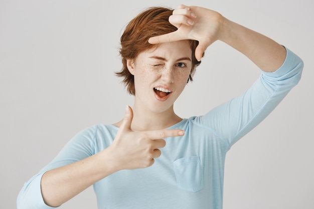 Carefree pretty redhead girl posing against the white wall