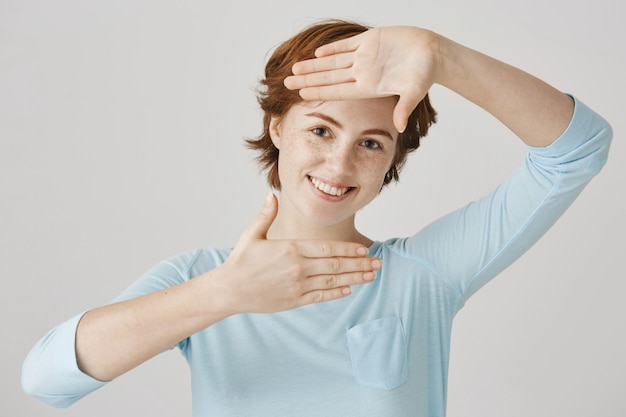 Carefree redhead girl posing against the white wall