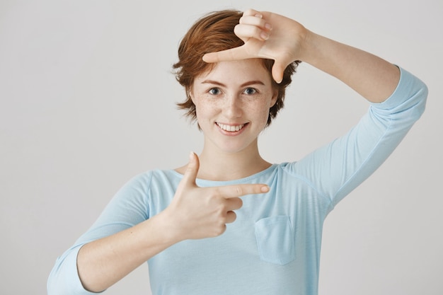 Carefree redhead girl posing against the white wall