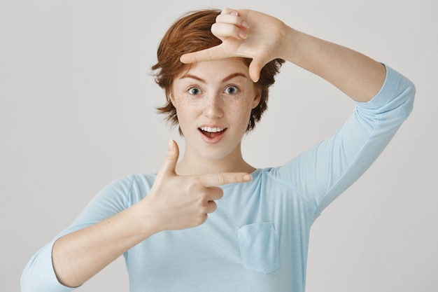 Carefree redhead girl posing against the white wall