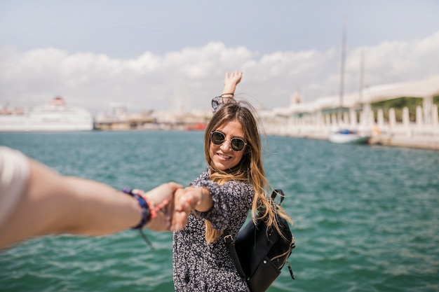 Carefree smiling young woman holding her boyfriend's hand