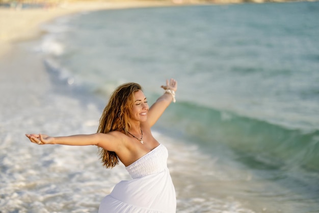 Carefree woman feeling free while standing at the shore with arms outstretched