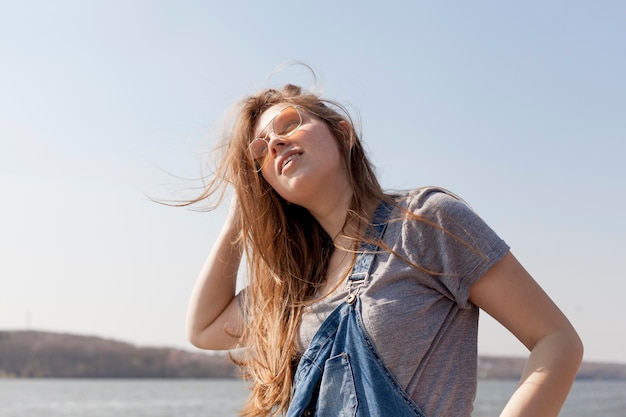 Carefree woman posing by the lake with sunglasses